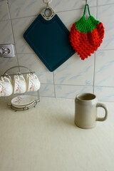 kitchen mugs on stand and knitted strawberry on wall