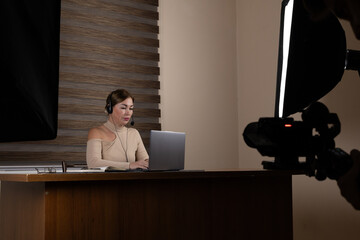 A woman is recording a news segment or podcast using professional studio
