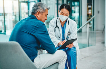 Obraz premium Medical professional wearing mask showing tablet to senior patient