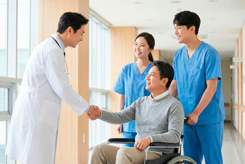 Obraz premium Doctor shaking hands with senior patient in wheelchair with medical team