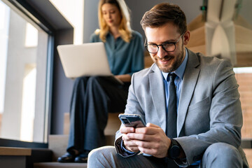 A confident business man leads her busy office life, multitasking with smartphone communication