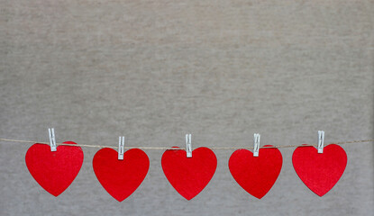 Five images of hearts are suspended on a thin rope.