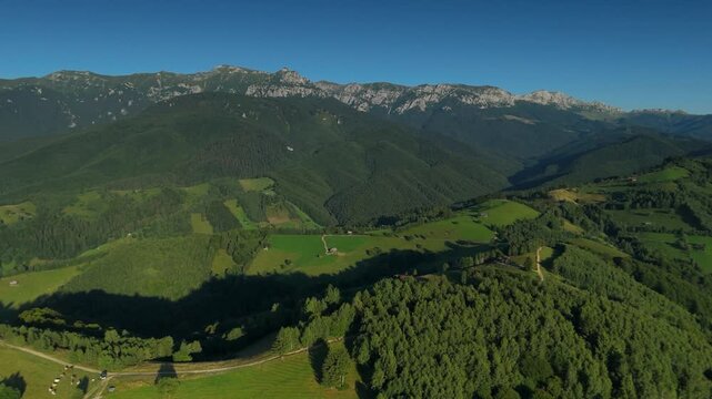High altitude lateral panorama of the western Bucegi Mountains ridge above green Carpathian hills near Simon in warm summer afternoon light