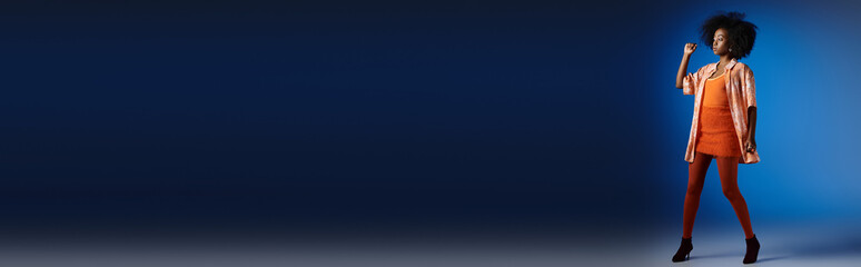 Curly young woman confidently showcases vibrant style against a striking blue background