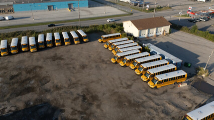 A lot of buses crowded in a depot, with drivers busy loading passengers