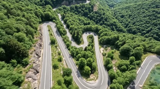 Aerial drone view of a winding mountain road with sharp hairpin turns cutting through a lush green forest and rocky terrain