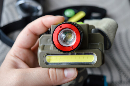 Close-up of a handheld LED headlamp with a red lens and COB light strip. Suitable for ads on camping equipment, outdoor lighting, DIY tools, and emergency gear.