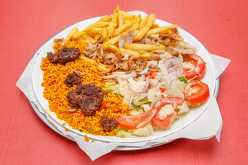 Assiette de köfte avec frites, salade et blé dur, fond rouge. Restauration rapide