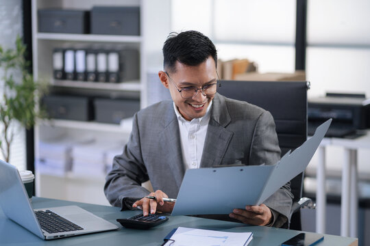 Business man working at office with laptop and documents on his desk, financial adviser analyzing data.