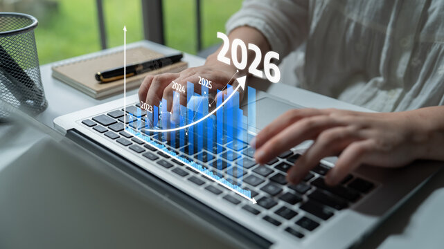 A person types on a laptop in a modern office, with a digital graph overlay representing business growth projections for 2026 and beyond, showcasing data analysis. Tessel