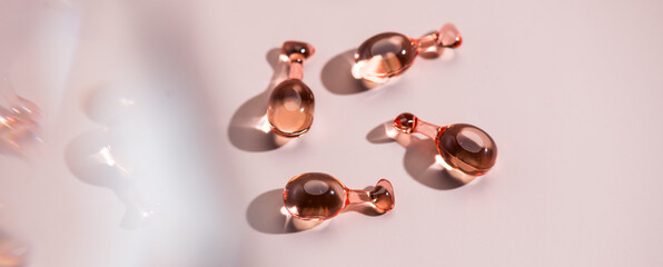 Skin care capsules face serum, revitalising capsule for youthful skin, collagen Professional cosmetics. Face care, pink liquid-filled capsules over beige. Beauty treatment. Top view, flat lay. 