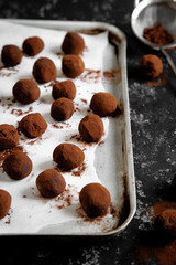 Homemade chocolate and gingerbread truffles coated in cocoa powder, arranged on a baking tray and served in a rustic dark setting. Ideal for festive, winter or Christmas-themed food and recipe content