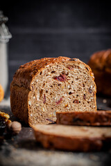 Rustic Christmas fruit bread filled with dried fruit, nuts and seeds, sliced and served on a dark textured surface. Ideal for festive, winter and holiday baking themes.