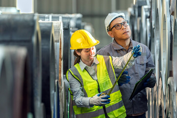 Two Manufactu Workers in Safety Gear Inspecting Large Industrial Machinery in a Factory Setting Using a Tablet and Clipboard for Quality Control and Maintenance