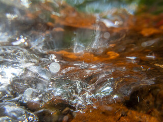 Abstract underwater closeup flowing stream over colorful stones nature background