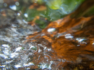 Abstract underwater closeup flowing stream over colorful stones nature background