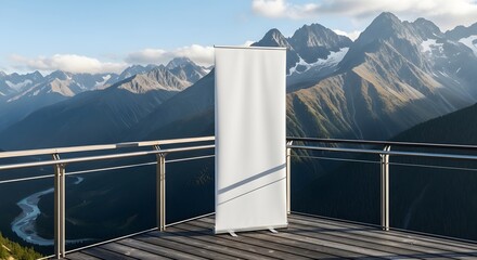Blank white rollup banner mockup standing on an outdoor wooden deck with a stunning panoramic view of snowcapped mountain range and valley below