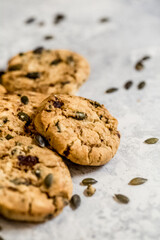 Golden muscovado sugar cookies studded with pumpkin seeds, arranged on a light textured surface. Ideal for baking themes, snack concepts and seasonal food content.