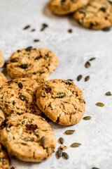 Golden muscovado sugar cookies studded with pumpkin seeds, arranged on a light textured surface. Ideal for baking themes, snack concepts and seasonal food content.
