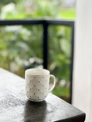 Simple wooden birdhouse with a triangular roof and circular entrance, suspended from above on a sculpted branch-like mount. 