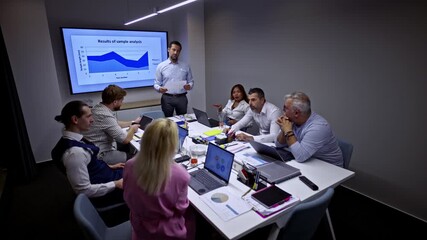 A diverse team of professionals actively participates in a corporate business meeting, reviewing detailed data analysis presented by a male colleague. - Powered by Adobe