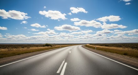 Endless highway journey under a bright sky dotted with fluffy cumulus clouds providing a sense of