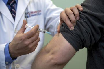 A doctor gives an injection into the arm of a sick man.
