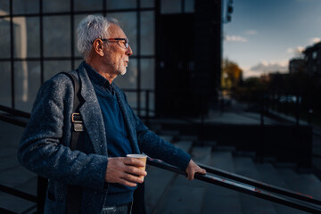 Senior man pausing, drinking coffee, contemplating city life