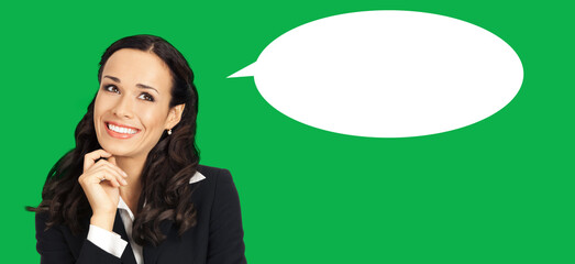 Portrait - happy smiling, looking up, thinking, thoughtful cute businesswoman woman wear black suit jacket, isolated green chroma key background with empty mockup speech bubble. Business ad concept