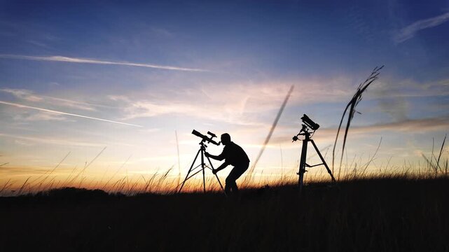 Amateur astro-photographer with a telescope and camera on a tripod photographing night sky with stars, planets, Moon and other celestial objects.	
