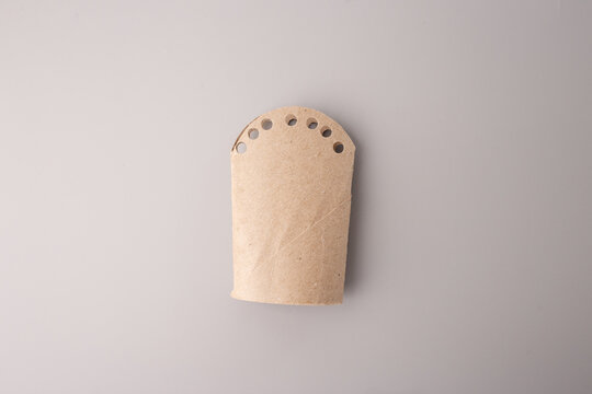 Recycled cardboard craft with punched holes, ideal for eco-friendly education, DIY tutorials, sustainability blogs, preschool activities, creative reuse campaigns, packaging or craft material branding