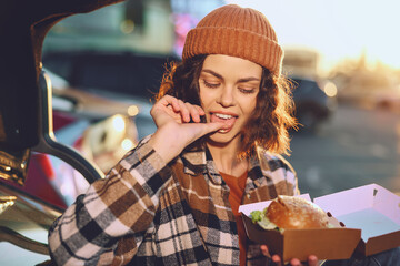 woman, burger, takeout, car, beanie, smile - candid lifestyle moment of a young woman eating a...