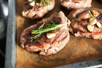 beef steaks with garlic and rosemary on a metal tray