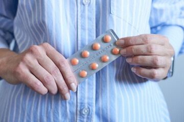 Close-up of a woman holding a blister pack of pills.