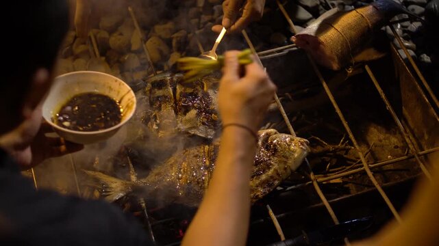 Delicious sea bream fish grilling on a barbecue, seasoned with lemon slices, emitting smoke and aroma.