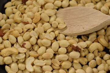 Raw green coffee beans scattered on a dark surface with a wooden spoon, showcasing the natural texture and color of unroasted coffee, ideal for culinary and beverage concepts