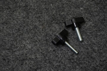 Two Black Plastic Knob Screws on Dark Gray Texture