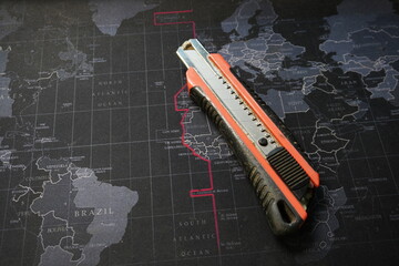 Utility Knife Resting on Dark Global World Map Background
