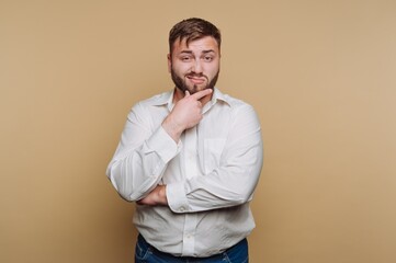 Confident man poses with thoughtful expression against a solid backdrop in a casual setting