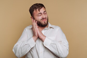 Man appears to express contentment while standing against a neutral background during indoor setting