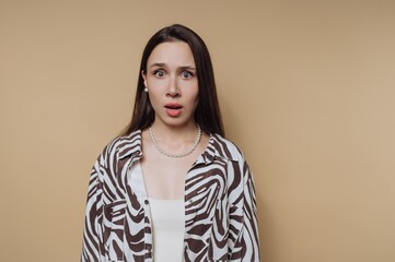 Surprised woman with long hair wearing zebra print shirt and pearls against a beige background