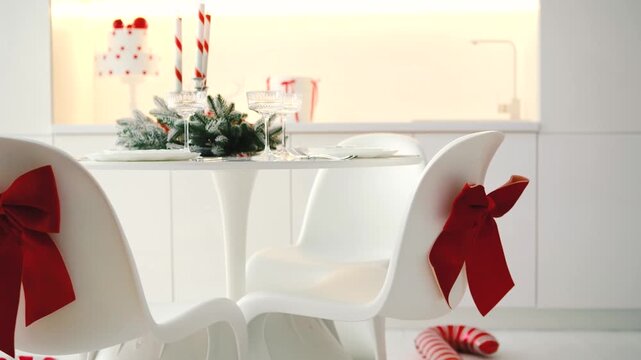 White chairs decorated with red bows sit at a table with festive holiday decorations and candy canes.