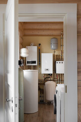 a boiler room with a window in a log country house. Advanced boiler room installation with various heating units and sophisticated pipe layout,  heating technology.