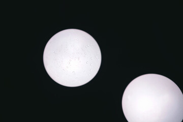 Two white spheres with water droplets against a dark background