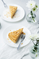 Napoleon cake slice with cream and puff pastry on white plate, delicate dessert