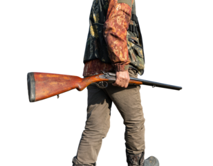 Mature man hunter with gun while walking on field.
