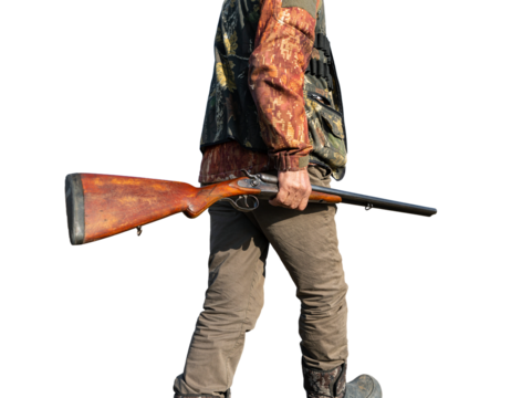 Mature man hunter with gun while walking on field.