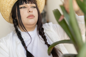 Woman wearing straw hat caring for house plant