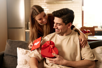 Happy couple celebrating Valentine's Day at home with card and heart-shaped gift box