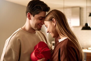 Romantic moment of a couple celebrating Valentine's Day with a heart-shaped gift box